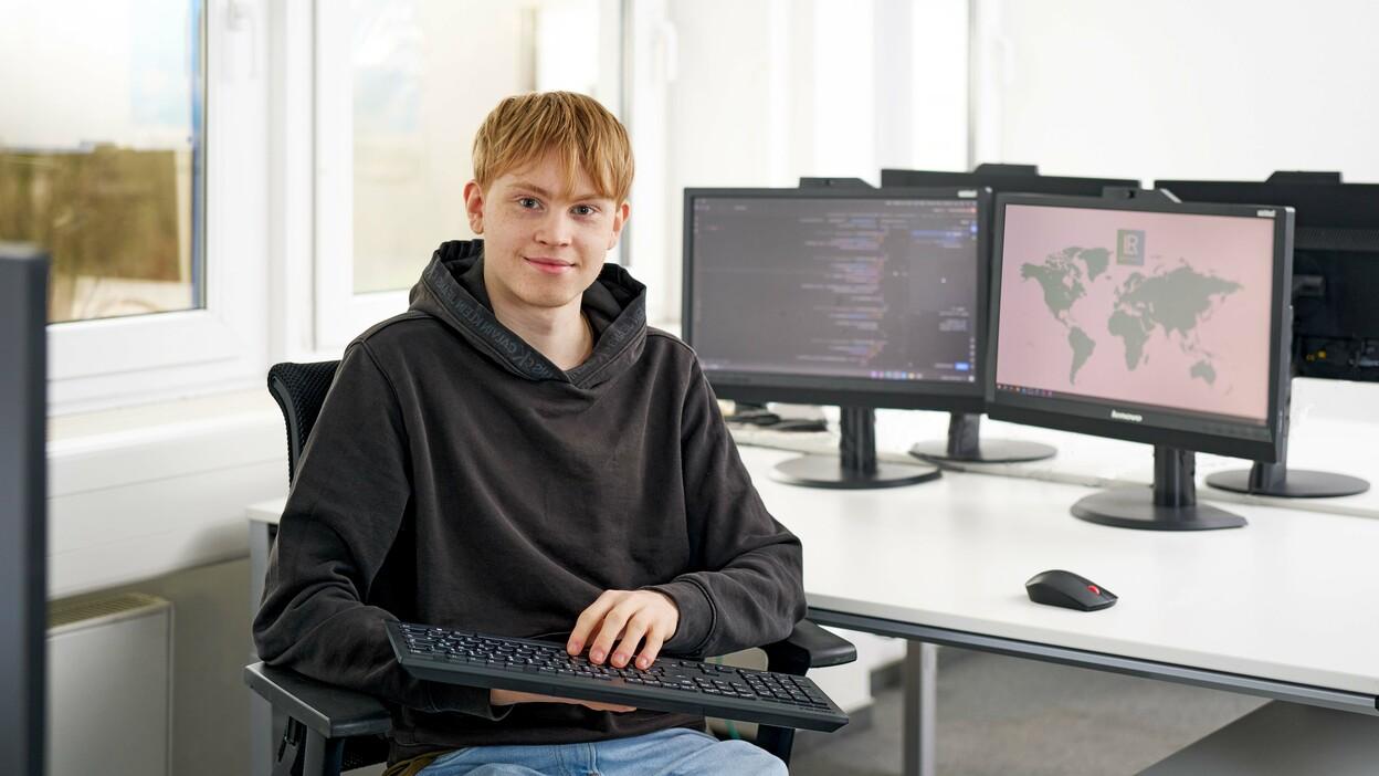 Auszubildender der Fachinformatik Anwendungsentwicklung arbeitet an einem Computer mit mehreren Monitoren.