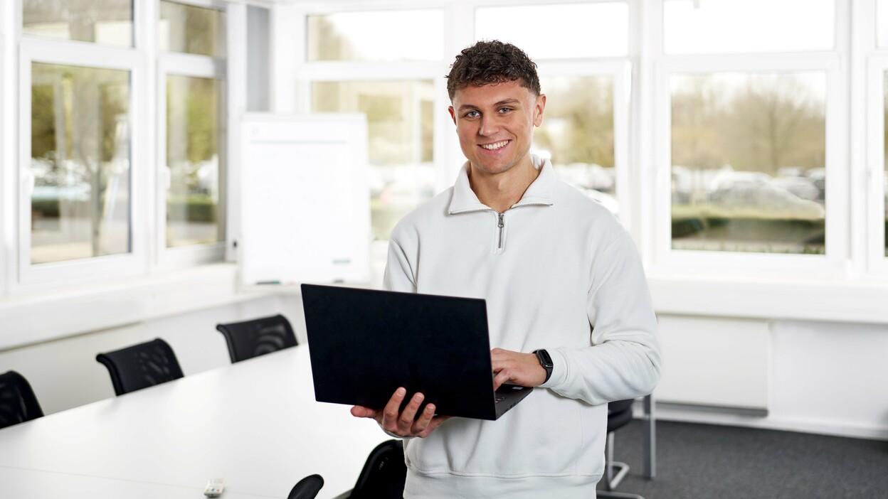 Auszubildender im dualen Studium BWL arbeitet mit einem Laptop in einem modernen Besprechungsraum.