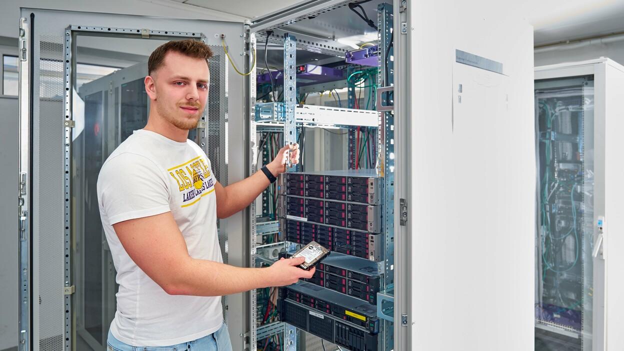 Auszubildender der Fachinformatik Systemintegration arbeitet an einem Serverschrank in einem Rechenzentrum.